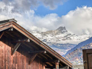 Experience the charm of alpine living with this stunning property, featuring rustic wooden architecture that perfectly complements the majestic snow-capped mountains in the background.