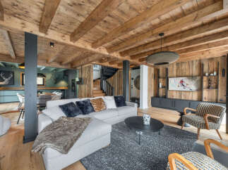 Experience rustic luxury in this stunning mountain chalet living room, featuring exposed wooden beams and a cozy sectional sofa perfect for gathering.