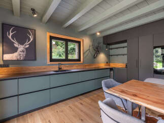 Experience rustic charm in this modern kitchen featuring sleek, sage green cabinetry and a rich wooden countertop.