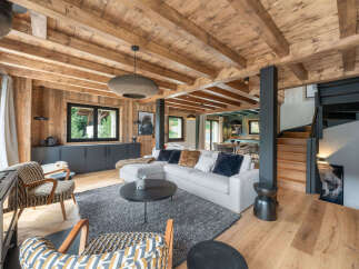 Experience luxurious mountain living in this stunning chalet, featuring a spacious open-plan living area with a modern sectional sofa and cozy armchairs.