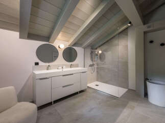 Experience modern luxury in this stunning bathroom, featuring a sleek double vanity with circular mirrors and contemporary lighting.