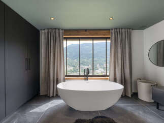 Experience ultimate relaxation in this luxurious bathroom featuring a freestanding soaking tub with a stunning mountain view.