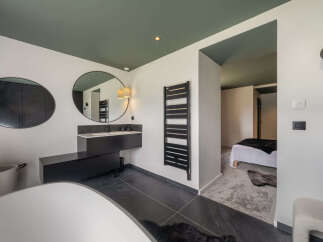 Experience modern luxury in this stunning bathroom featuring a sleek floating vanity with a minimalist sink and a large round mirror.