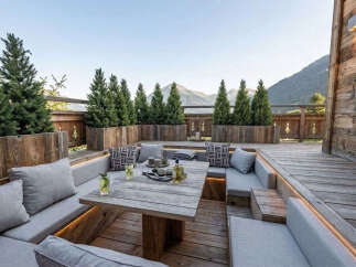 Experience luxurious outdoor living with this stunning mountain retreat featuring a spacious wooden deck and integrated seating.