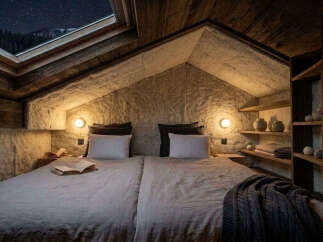 Experience the magic of stargazing from this unique attic bedroom, featuring a stunning skylight with a view of the night sky and surrounding mountains.