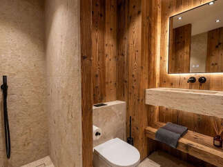 Experience rustic luxury in this stunning bathroom, featuring a sleek stone vanity with integrated sink and a modern wall-mounted toilet.