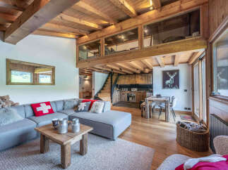 Experience rustic charm in this stunning mountain retreat, featuring a cozy living area with a plush sectional sofa and a rustic wooden coffee table.