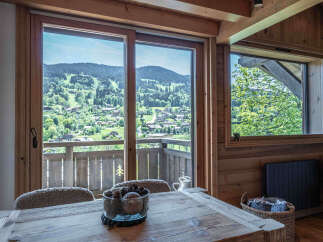 Experience breathtaking mountain views from this charming chalet, featuring a spacious dining area with a rustic wooden table and comfortable seating.