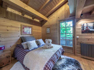 Experience cozy mountain living in this charming wooden bedroom, featuring a comfortable bed adorned with plush pillows and a soft throw.