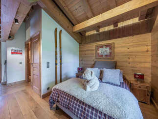 Experience rustic charm in this cozy mountain bedroom, featuring exposed wooden beams and walls that exude alpine warmth.