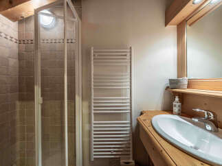 This charming bathroom features a spacious shower with tiled walls and a glass enclosure, perfect for a refreshing start to your day.