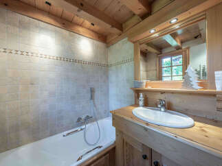 Experience rustic charm in this bathroom featuring a tiled bathtub and shower area complemented by warm wooden beams and cabinetry.