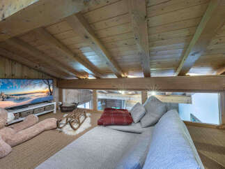 Experience cozy living in this charming loft space, featuring a large flat-screen TV perfect for movie nights and a plush oversized teddy bear for ultimate comfort.