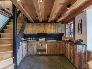 Experience rustic charm in this mountain-inspired kitchen, featuring warm wooden cabinetry and exposed beams.