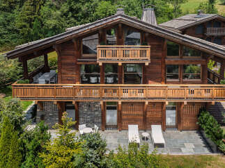 Experience luxury mountain living in this stunning wooden chalet, nestled amidst lush greenery.