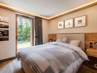 Experience ultimate comfort in this beautifully appointed bedroom, featuring a plush king-size bed adorned with a stylish grey and white striped blanket.