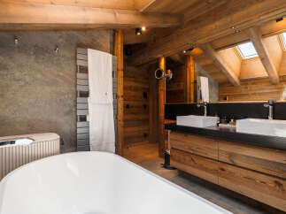 Experience rustic luxury in this stunning bathroom, featuring a deep soaking tub and a double vanity with modern vessel sinks.