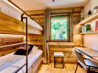 Experience cozy living in this charming room featuring rustic wooden walls and a comfortable bunk bed setup.