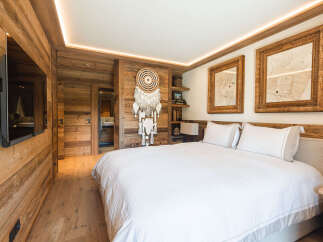 Experience rustic luxury in this charming bedroom, featuring warm wood paneling and a cozy ambiance.