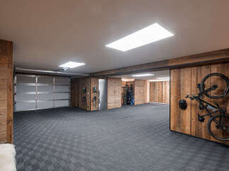 Discover this modern garage featuring a sleek, sectional garage door and durable, interlocking tile flooring.