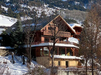 Experience the charm of this stunning wooden chalet nestled in a picturesque snowy mountain landscape.