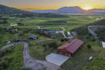Experience serene mountain living with this stunning property featuring a spacious home with a vibrant red roof, nestled amidst rolling green hills.