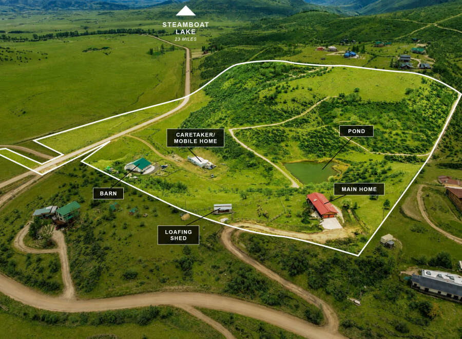 Discover this expansive property featuring a main home, caretaker's mobile home, and a barn, all nestled within a picturesque landscape.