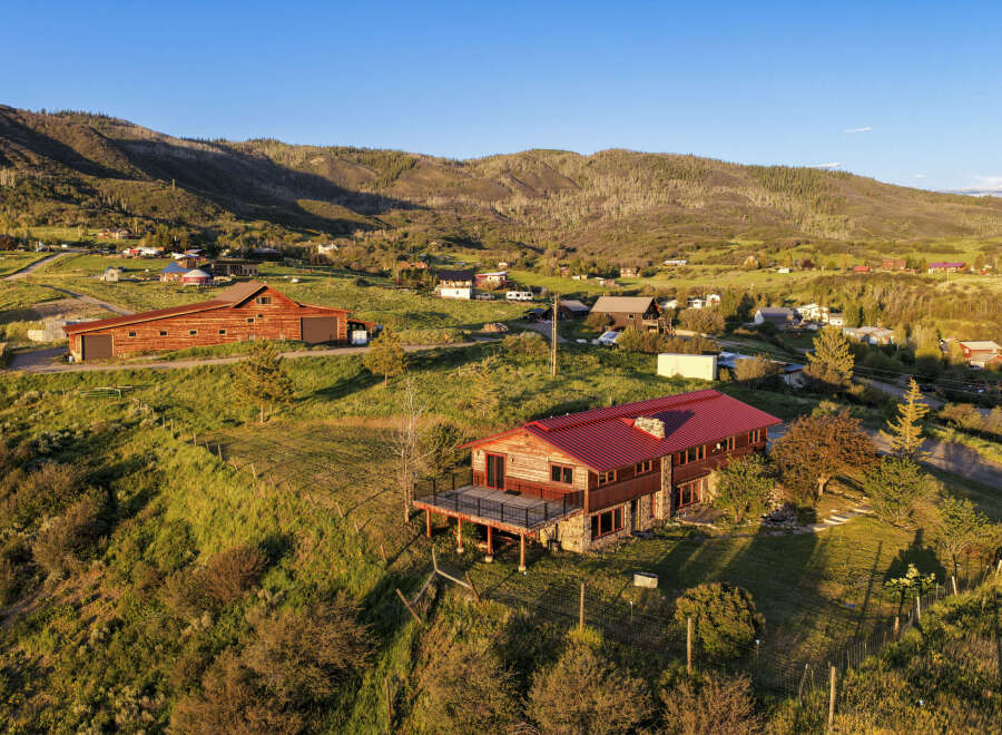 Discover this stunning mountain retreat featuring a spacious log home with a durable red metal roof and a large deck perfect for enjoying the breathtaking panoramic views.