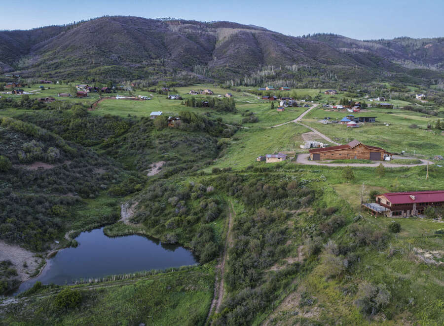 Discover this stunning property nestled in a picturesque mountain landscape, featuring a charming pond and expansive green fields.