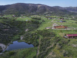 Discover this stunning property nestled in a picturesque mountain landscape, featuring a charming pond and expansive green fields.
