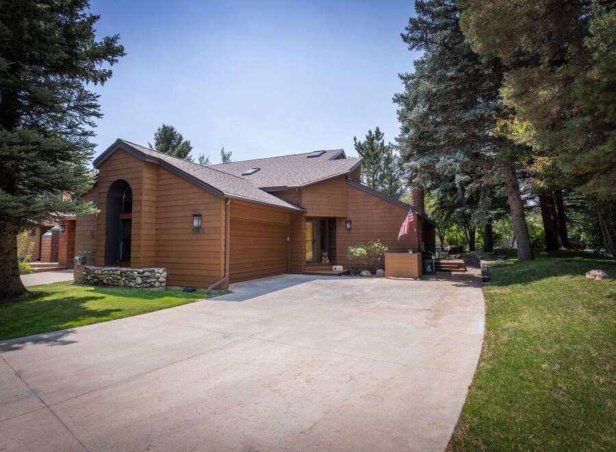 Nestled amidst mature trees, this charming brown wood-sided home offers a serene retreat.