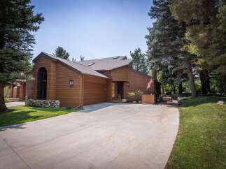 Nestled amidst mature trees, this charming brown wood-sided home offers a serene retreat.