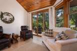Experience rustic charm in this inviting living space featuring a vaulted wood-paneled ceiling and large sliding glass doors that open to a lush outdoor setting.