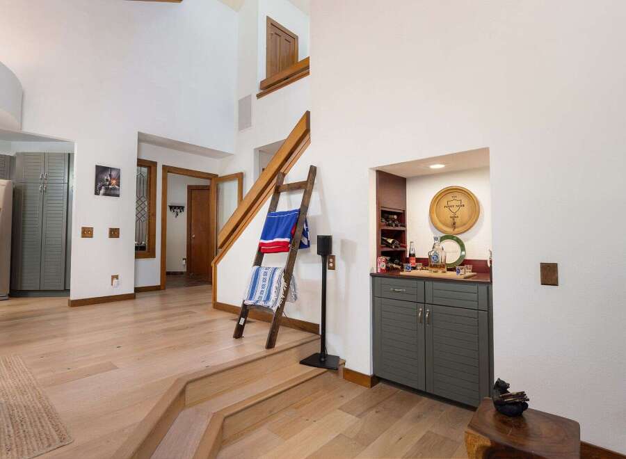 Step into this inviting entryway featuring a beautiful wooden staircase and a cozy built-in bar area perfect for entertaining.