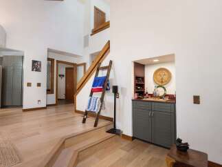 Step into this inviting entryway featuring a beautiful wooden staircase and a cozy built-in bar area perfect for entertaining.