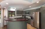 Discover this beautifully updated kitchen featuring sleek, gray shaker cabinets and a stunning curved, dark wood breakfast bar.