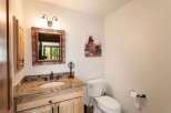 This charming bathroom features a rustic wooden vanity with a granite countertop and a tiled backsplash, complemented by a decorative mirror and a whimsical bear-themed artwork.