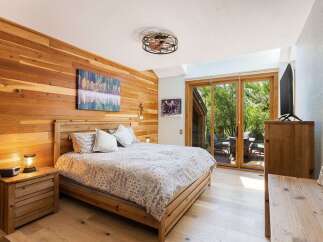 Experience rustic charm in this beautifully appointed bedroom, featuring warm cedar plank walls and a comfortable wooden bed.