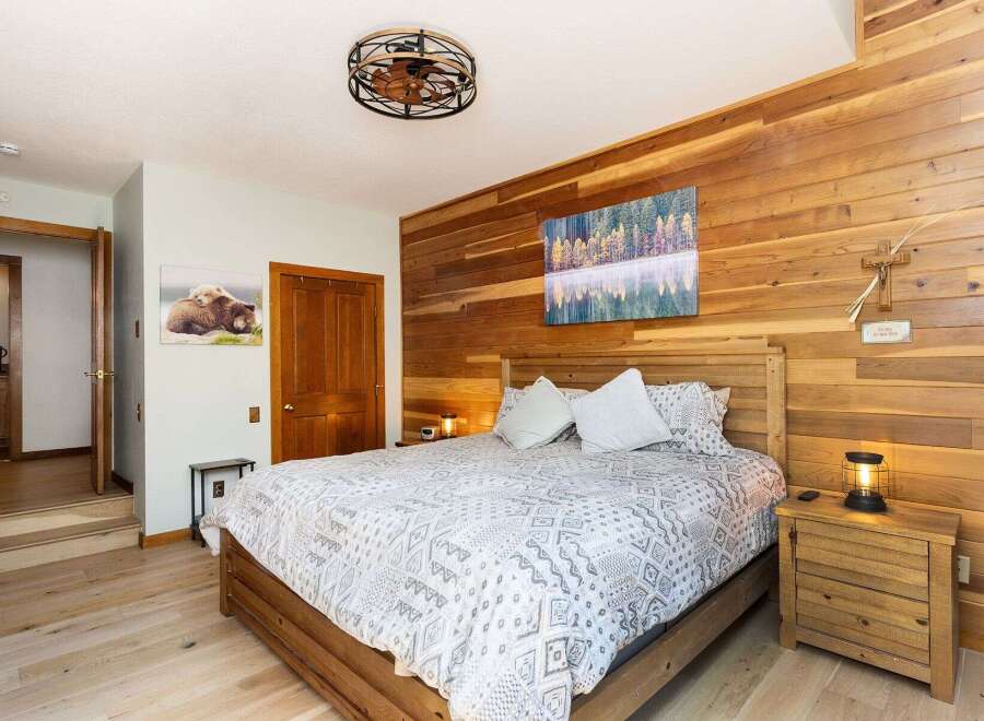 Experience rustic charm in this inviting bedroom, featuring a cozy wooden bed and a striking accent wall of natural wood planks.