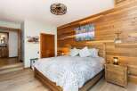 Experience rustic charm in this inviting bedroom, featuring a cozy wooden bed and a striking accent wall of natural wood planks.