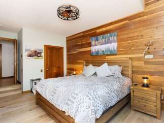 Experience rustic charm in this inviting bedroom, featuring a cozy wooden bed and a striking accent wall of natural wood planks.