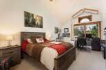 This charming bedroom features a rustic wooden bed with a patchwork quilt, complemented by a matching nightstand and lamp.