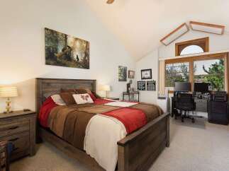 This charming bedroom features a rustic wooden bed with a patchwork quilt, complemented by a matching nightstand and lamp.