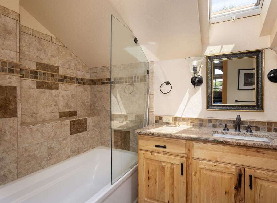 This charming bathroom features a spacious bathtub with a glass shower enclosure and elegant tile work.