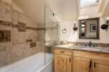 This charming bathroom features a spacious bathtub with a glass shower enclosure and elegant tile work.