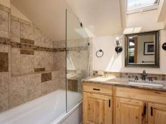 This charming bathroom features a spacious bathtub with a glass shower enclosure and elegant tile work.