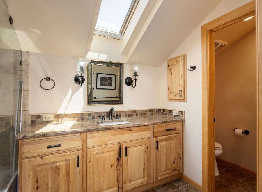 Discover this charming bathroom featuring a spacious vanity with a granite countertop and ample wooden cabinetry.