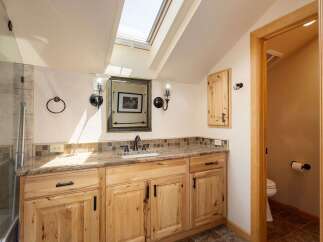 Discover this charming bathroom featuring a spacious vanity with a granite countertop and ample wooden cabinetry.