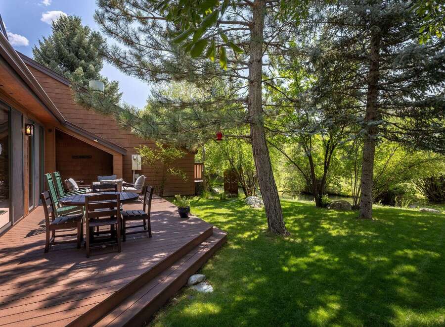 Enjoy outdoor living on this spacious wooden deck, perfect for al fresco dining or relaxing with a view of the lush, green backyard.