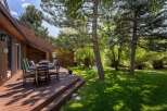 Enjoy outdoor living on this spacious wooden deck, perfect for al fresco dining or relaxing with a view of the lush, green backyard.
